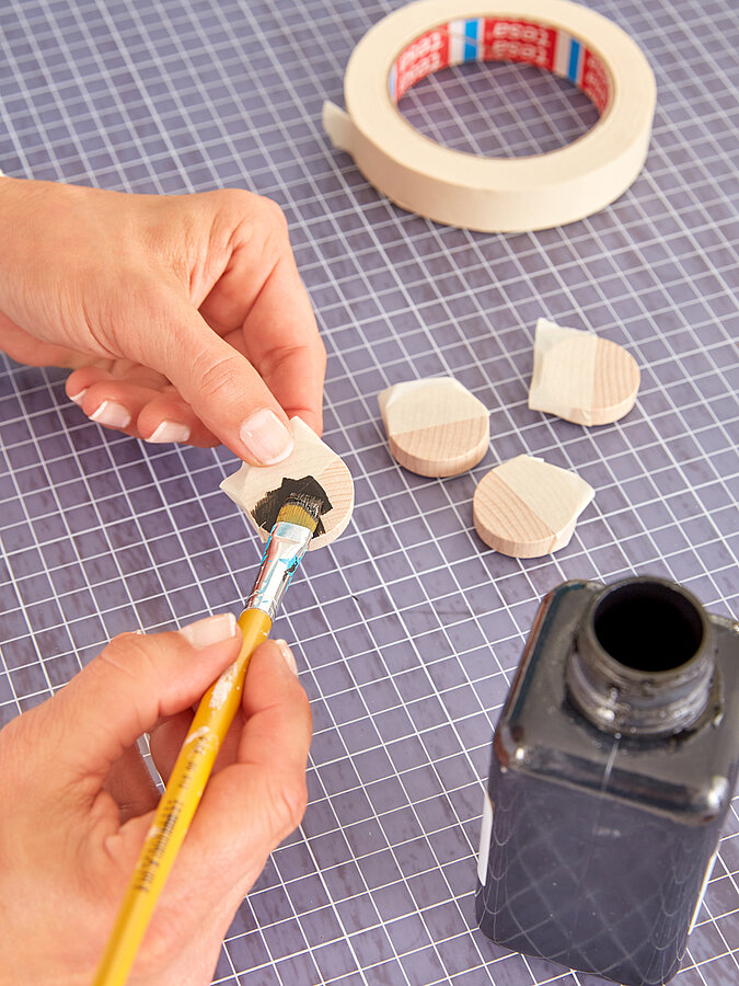 Backgammon Spiel: Holzspielsteine werden mit Acrylfarbe schwarz bemalt.