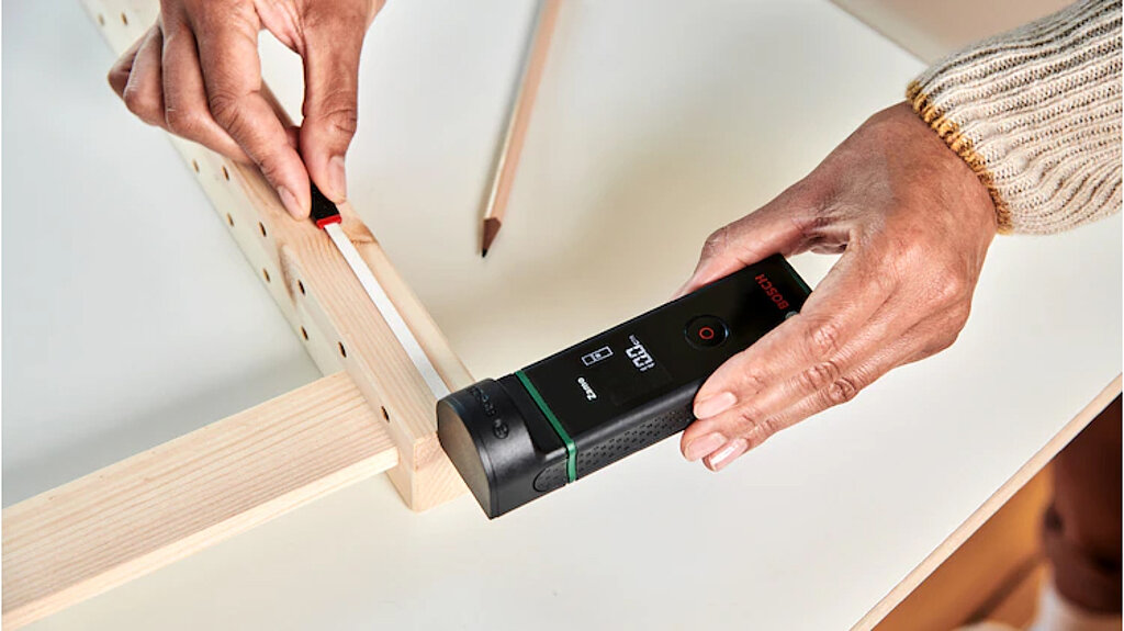 Vom Regal zum Adventskalender: Mit einem Laser-Entfernungsmesser und Bleistift werden die Bohrpunkte für die Wandbefestigung am Holzrahmen markiert.