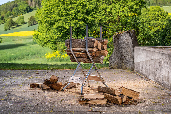 Auf einem Sägebock liegen Holzstücke bereit, um sie auf die passende Länge für Brennholz zu sägen.