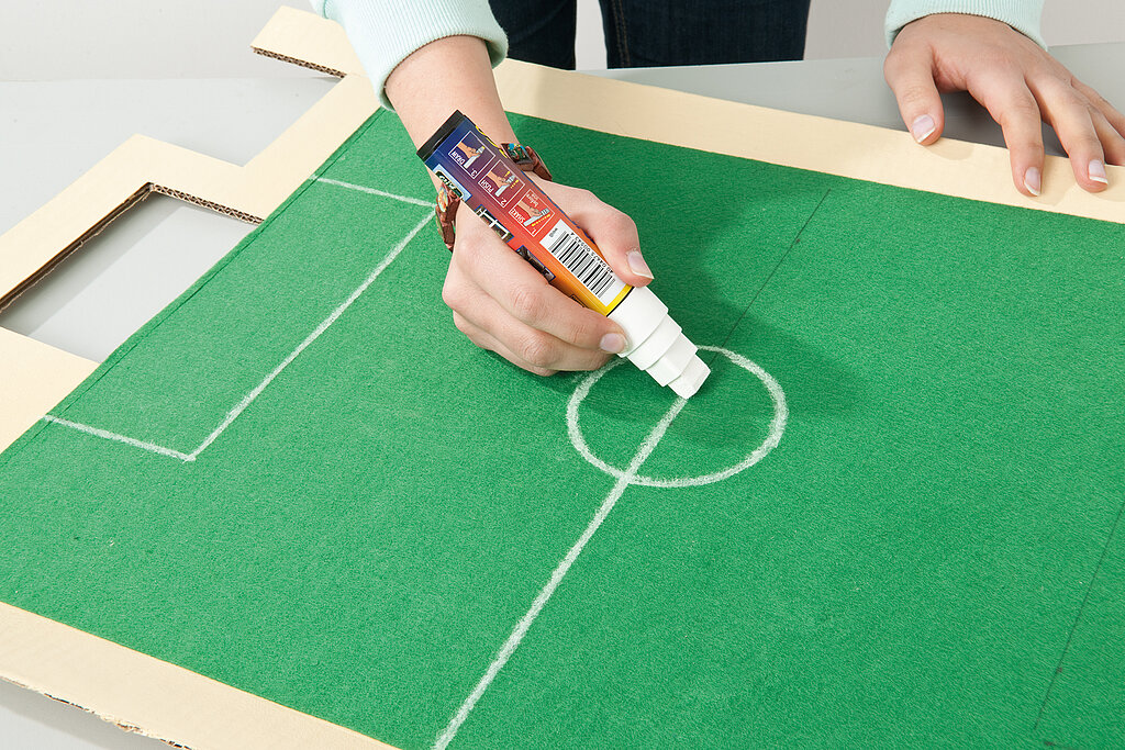 Tipp Kick basteln: Spielfeldmarkierungen werden auf dem grünen Filz mit einem Textilmarker nachgezogen