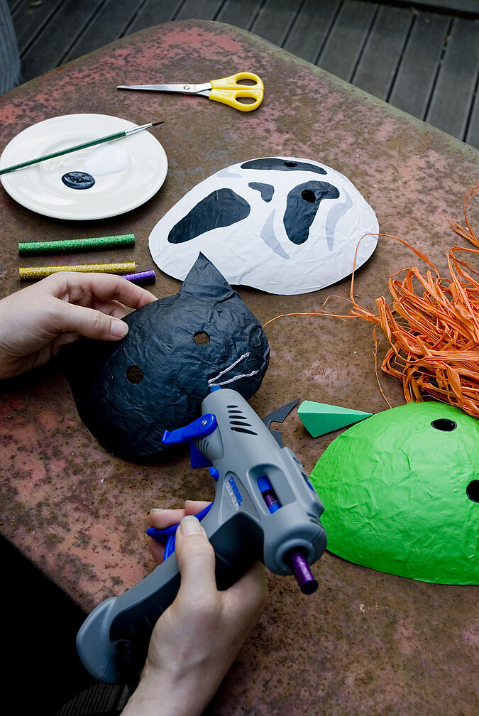 Halloween-Kostüm selber machen: Eine schwarze Katzenmaske aus Pappmaché wird mit einem Multifunktionswerkzeug verziert.