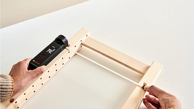 Vom Regal zum Adventskalender: Mit einem Laser-Entfernungsmesser werden die Abstände am Holzrahmen kontrolliert und die Befestigungspunkte markiert.