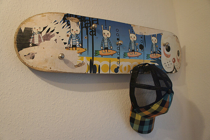 WG Zimmer einrichten mit einer DIY-Garderobe aus einem alten Skateboard als kreative Lösung für Jacken, Caps und Taschen.