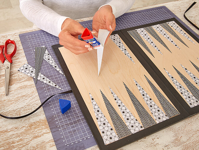 Backgammon Spiel: Papierdreiecke werden für das typische Spielfeld aufgeklebt.