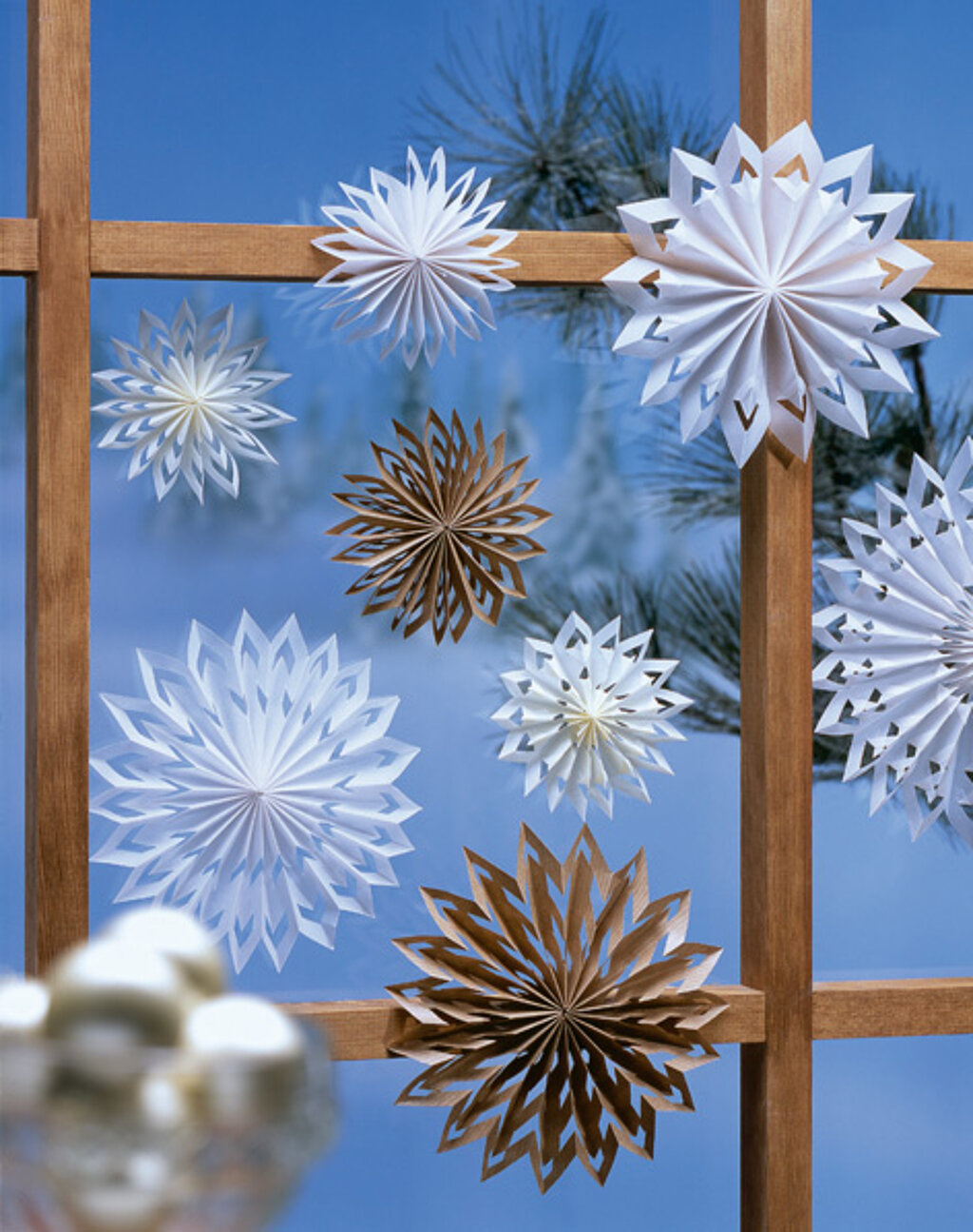 kunstvoll gefaltete weisse und naturfarbene Papiersterne an einem Fenster befestigt