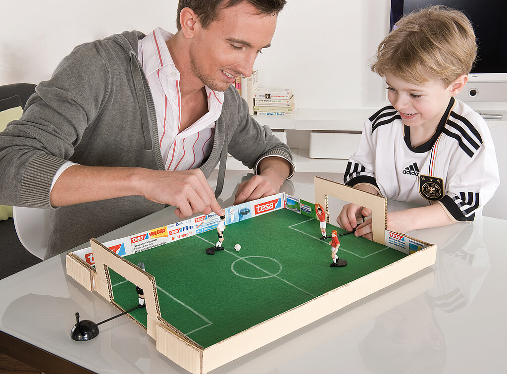 Tipp Kick basteln: Vater und Sohn spielen begeistert an einem selbst gebastelten Tipp Kick