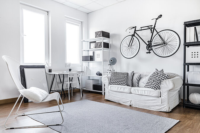 WG Zimmer einrichten mit platzsparender Fahrradhalterung an der Wand und heller, funktionaler Einrichtung für kleine Räume.