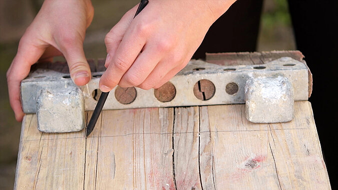 DIY-Bett aus Gerüstbohlen beim Anzeichnen der Schnittlinie auf einer gebrauchten Gerüstbohle