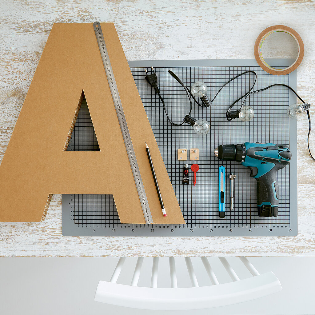 Materialien und Werkzeuge zum Basteln eines Leuchtbuchstabens aus Wellpappe