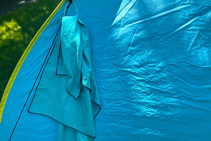 Festival Gadgets nasses Handtuch hängt am Zelt in improvisierter Kabelbinder-Schlaufe