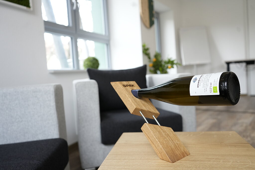 Eine Weinflasche steckt waagerecht in einer Halterung aus Holz