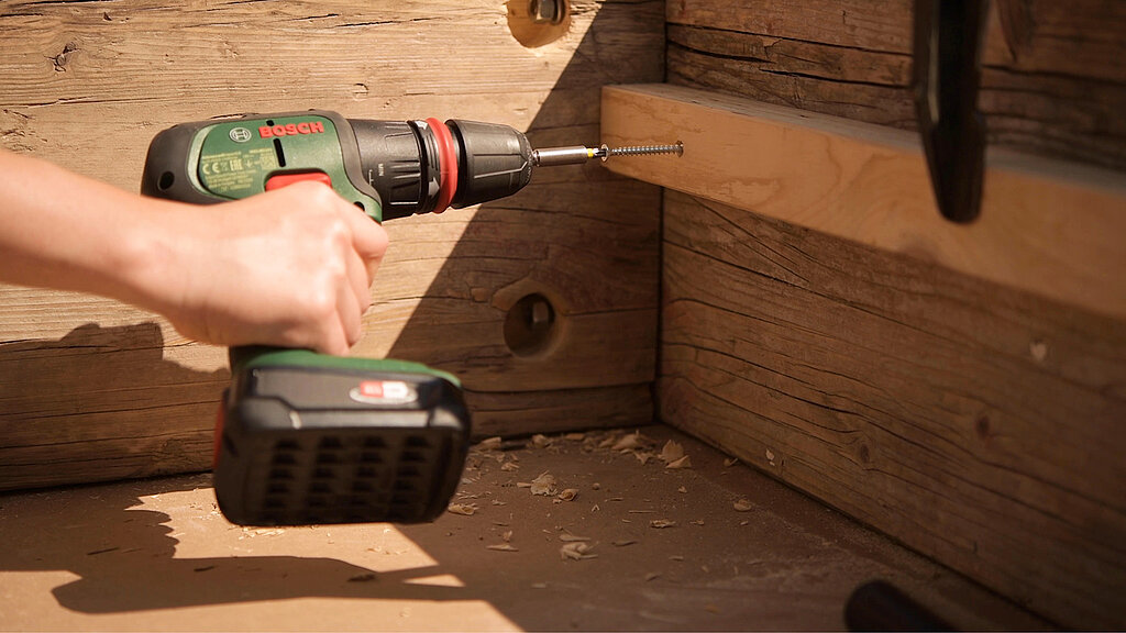 DIY-Bett aus Gerüstbohlen beim Verschrauben der inneren Holzleiste für die Auflage des Lattenrostes
